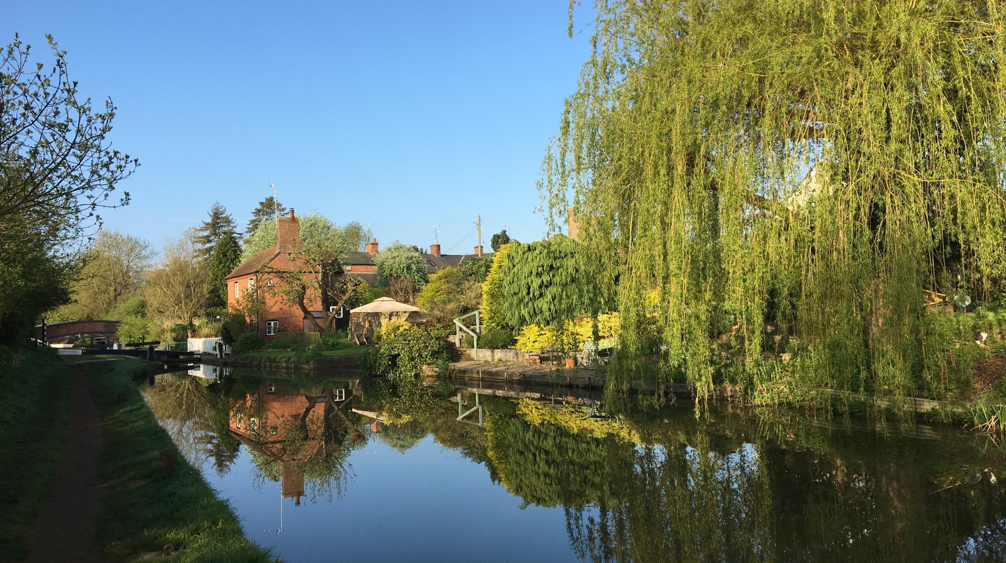 Canal lock with reflections of willow tree in calm canal water